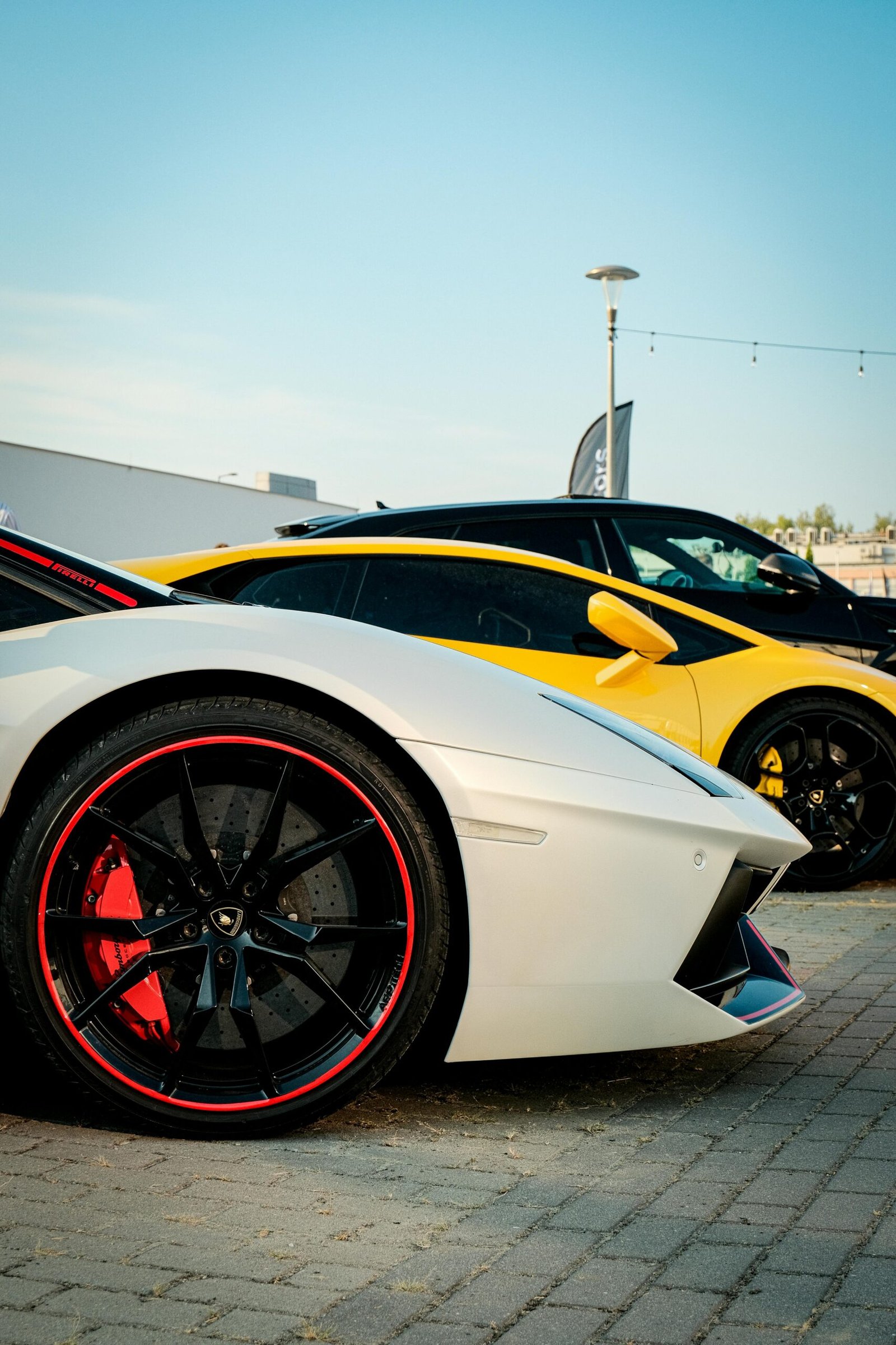 Two luxury sports cars parked side by side in an urban area under clear skies.